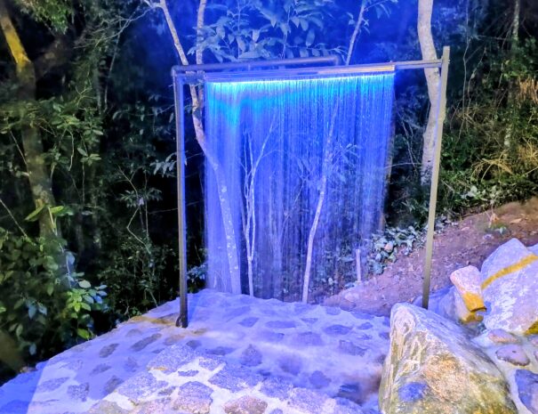 Cascata fria em inox com LED no pátio: um banho gelado revigorante, a poucos passos da suíte — e um cenário lindo para fotos.