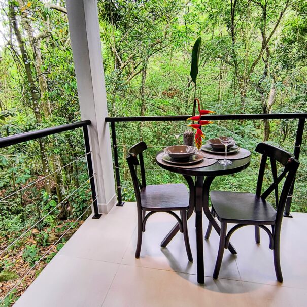 Cantinho da varanda com vista para a mata — ótimo para café da manhã, um almoço leve ou trabalho com tranquilidade.
