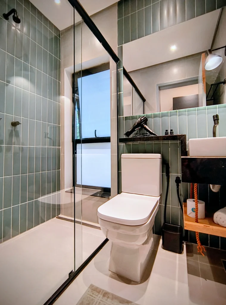Banheiro privativo moderno, com acabamento elegante e ducha confortável.