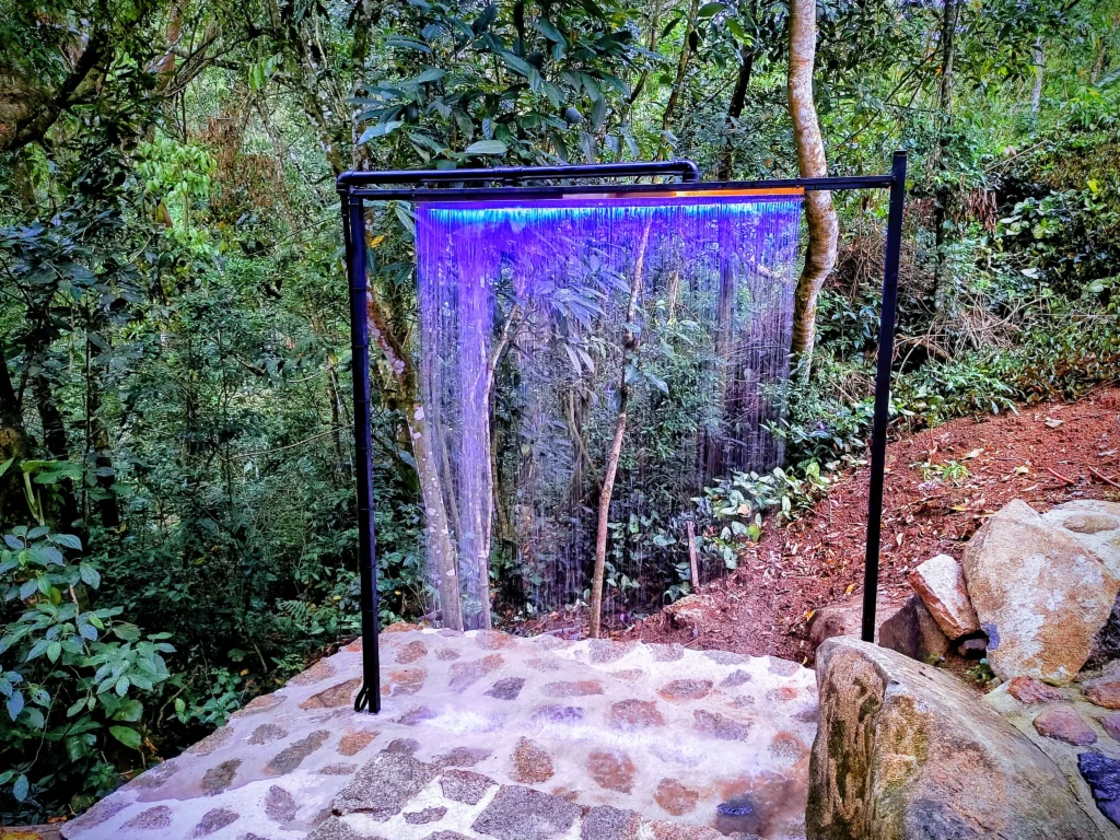 Cascata fria iluminada na área externa — banho revigorante a poucos passos da suíte.